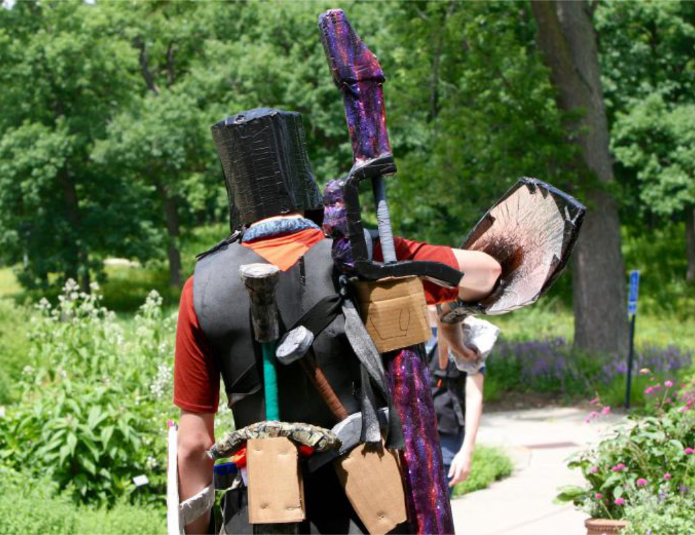 A LARPer loaded with gear heads across the footbridge at Silverwood Park during the annual game of Dragonwood LARP vs the Nature Protectors Summer Camp. 2022. Saint Anthony Village, Minnesota, USA. Photo by Nic Rosenau. All rights reserved.