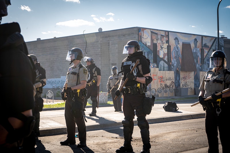 Photo of police officers standing guard towards George Floyd protestors in Minneapolis riots by munshots on Unsplash.