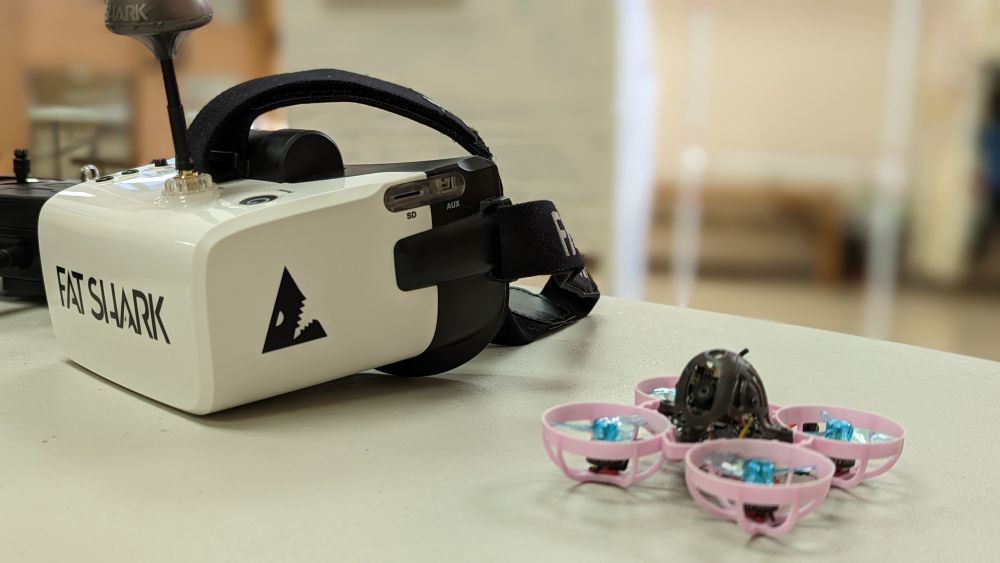 Pink and blue tiny whoop drone with white and black googles during a Fall 2022 meeting of the PHS Micro Track Smash Tiny Whoop Drone Racing Team