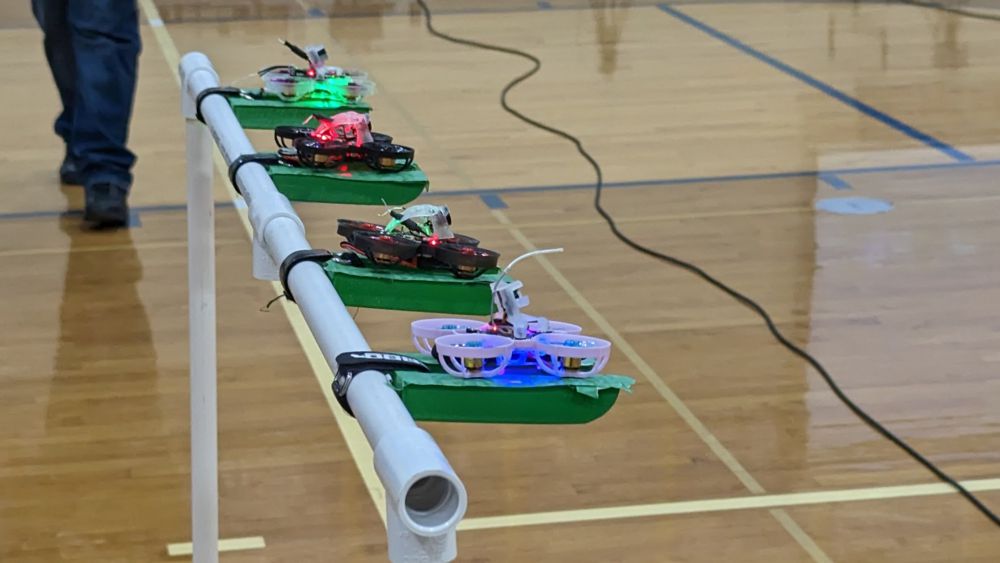 Four tiny whoop drones on the start gate.