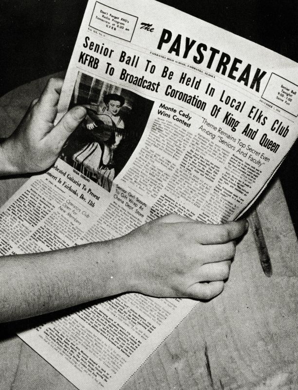 A student holds up a copy of a school newspaper, The Paystreak.