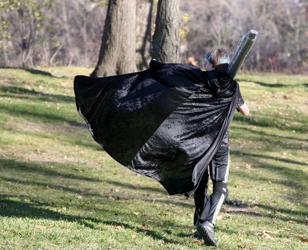 A young LARPer's cape billows in the wind as we walks away while LARPing at Silverwood Park in Saint Anthony Village, Minnesota, USA.
