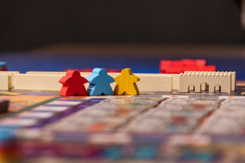 Red, blue, and yellow meeple figures in the game Merv.
