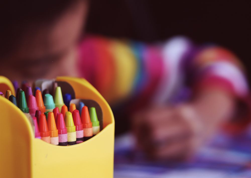 Crayons beside a child coloring.