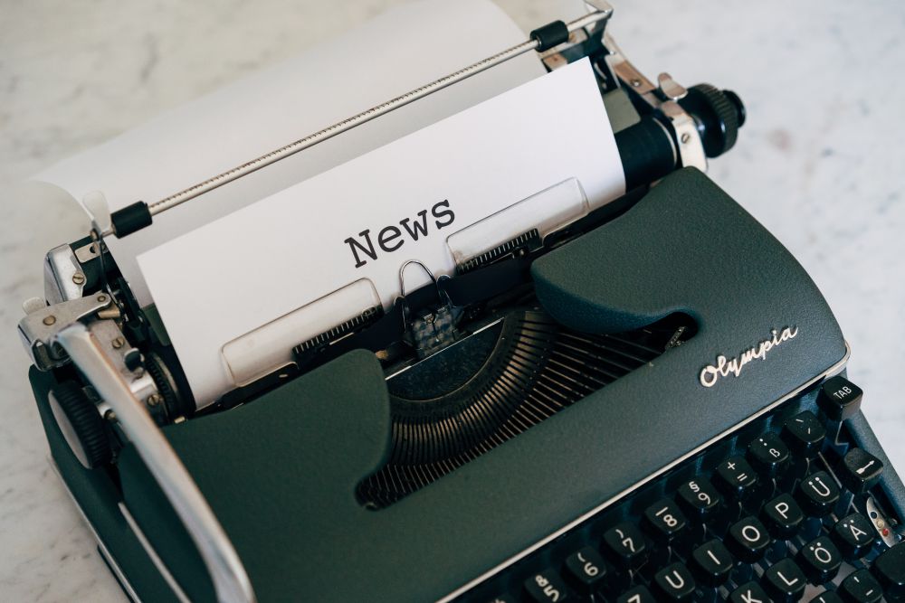 Closeup of an old fashioned Olympia typewriter with a sheet paper. The top of the sheet reads News. 2020. Photo by Markus Winkler on Unsplash.
