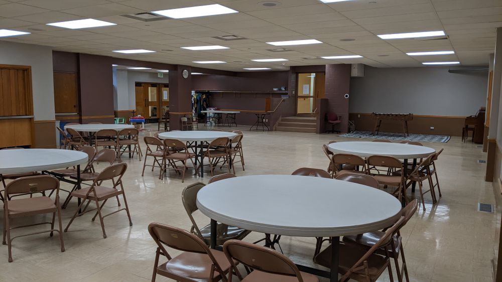a large room with five five-foot round folding tables surrounded by 8 fold chairs each with an open area behind them